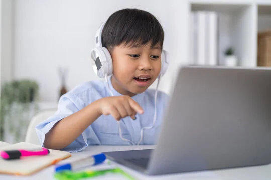 A young boy following his first lesson on a laptop